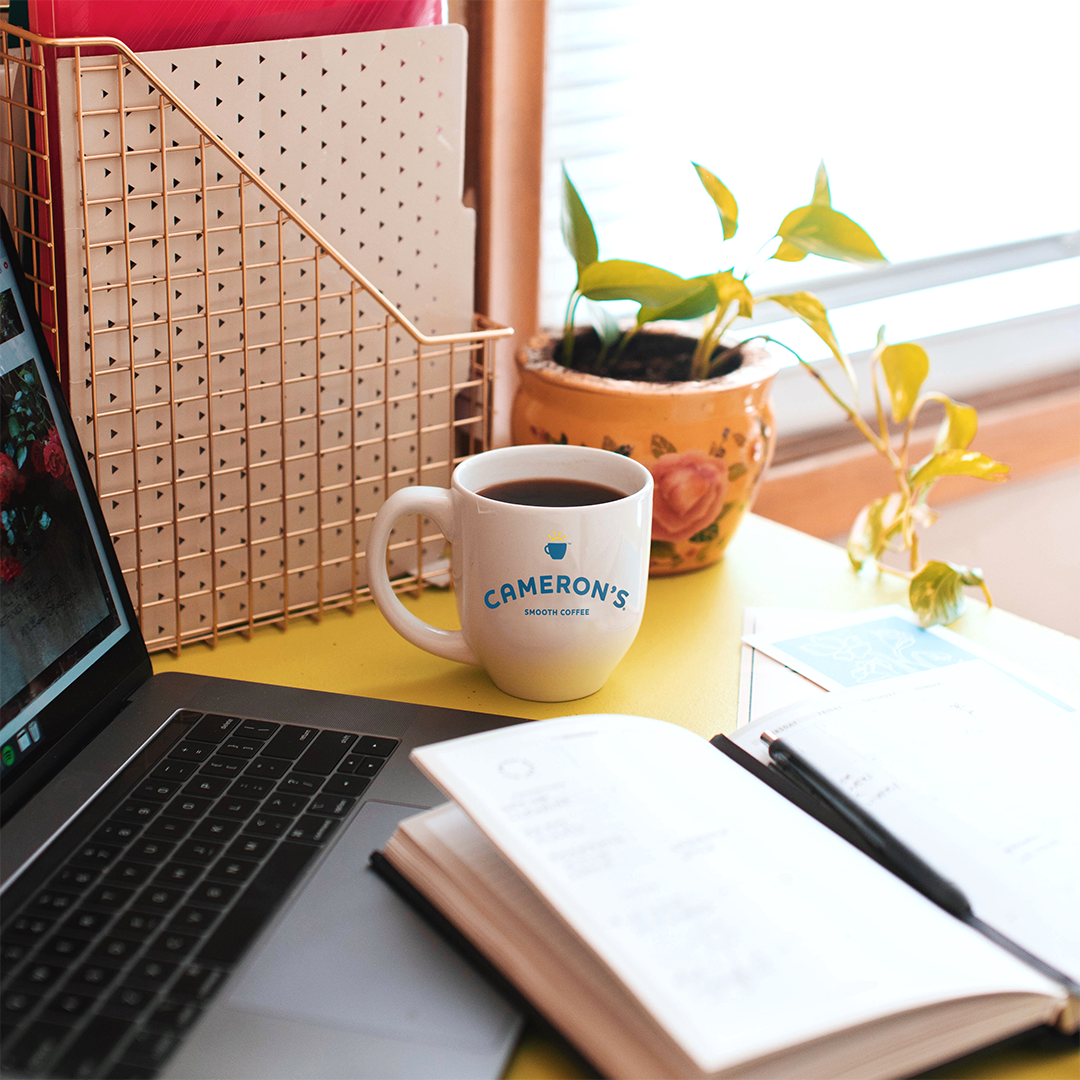 Cameron's Coffee Mug on desk with notebook and laptop