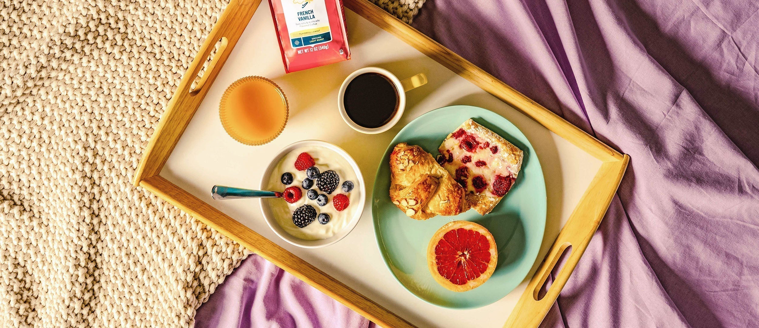 Tray of camerons coffee and breakfast foods on a bed