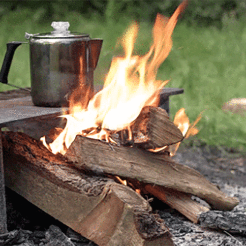 Coffee percolator sitting next to a campfire