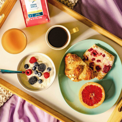 Tray of camerons coffee and breakfast foods on a bed