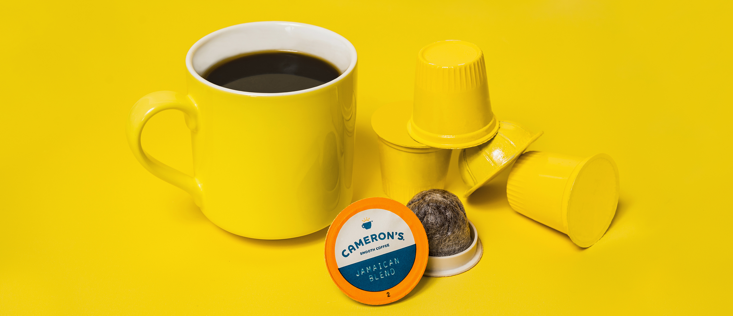 Bright yellow background with a cup of coffee and various coffee pods